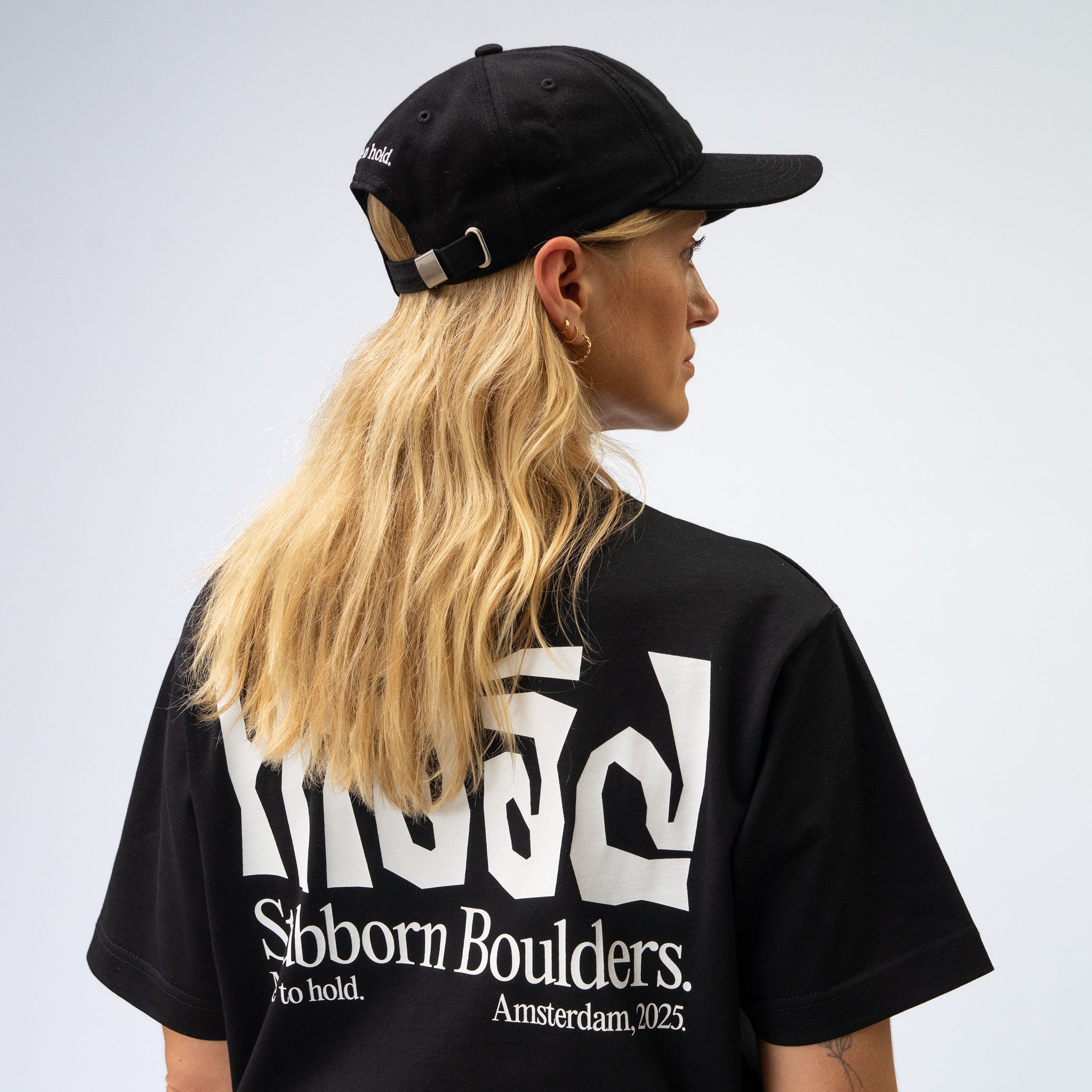 Person wearing a black cap and black t-shirt with white text on a light gray background