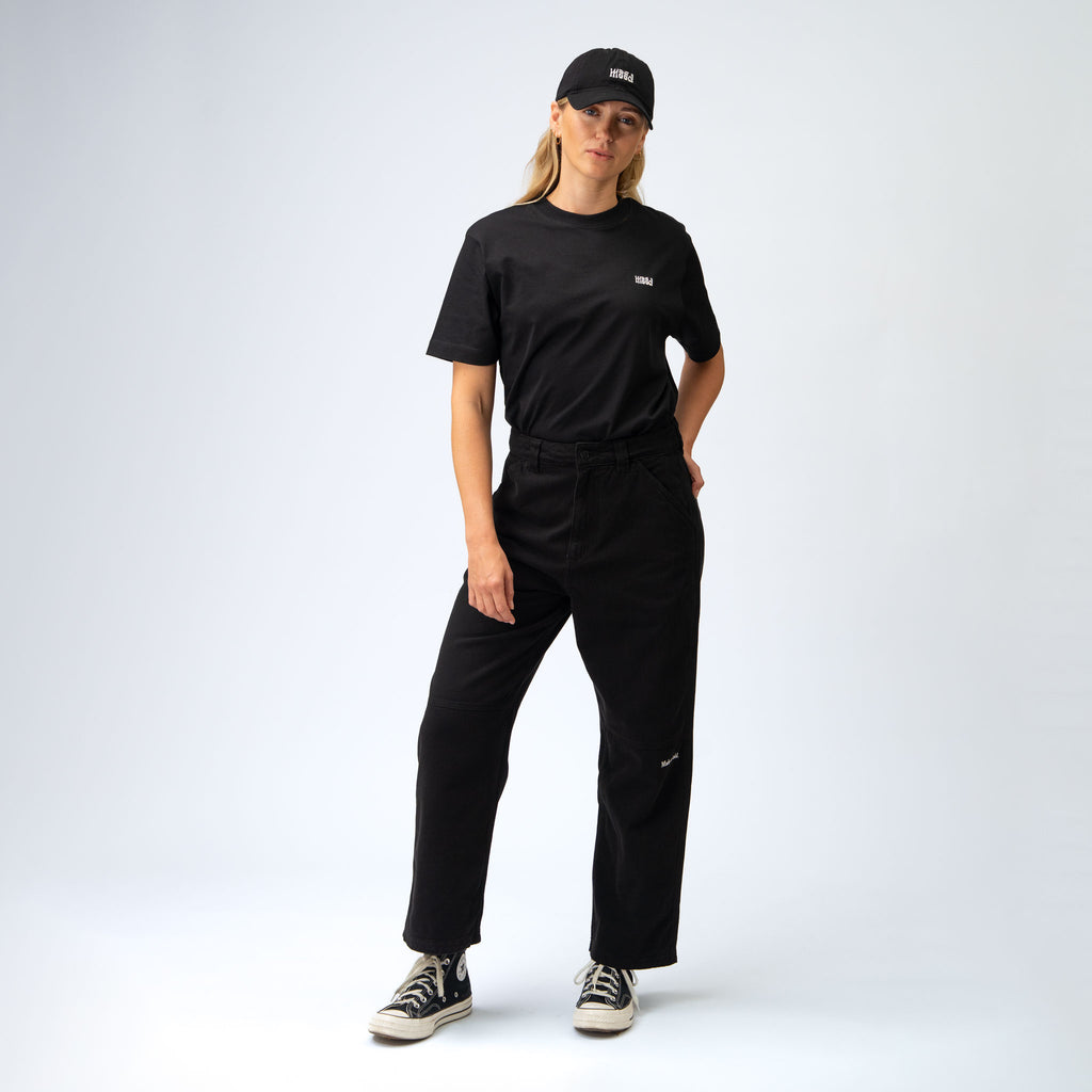 Person wearing a black outfit with a cap on a white background