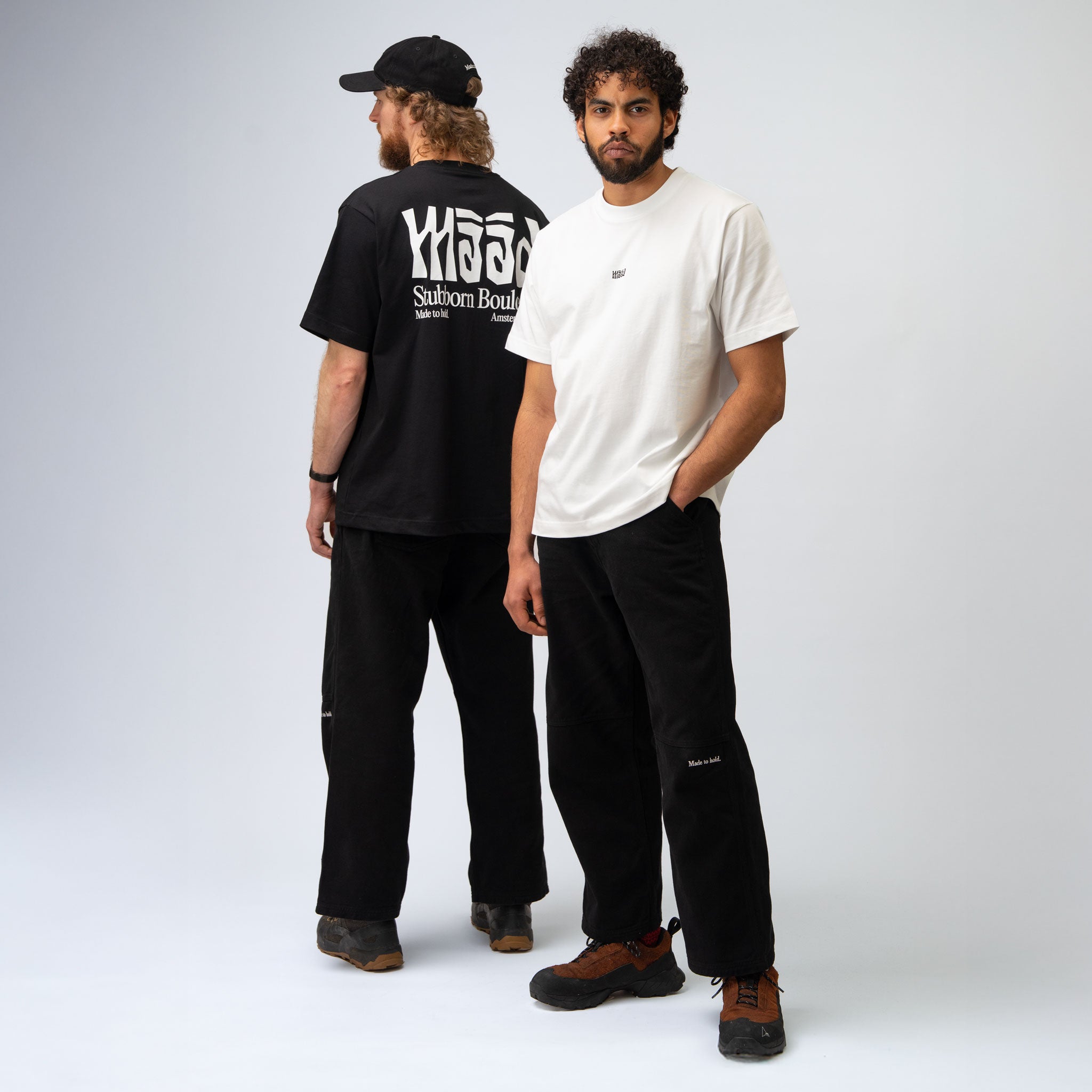 Two men wearing black and white t-shirts with visible branding on a plain background